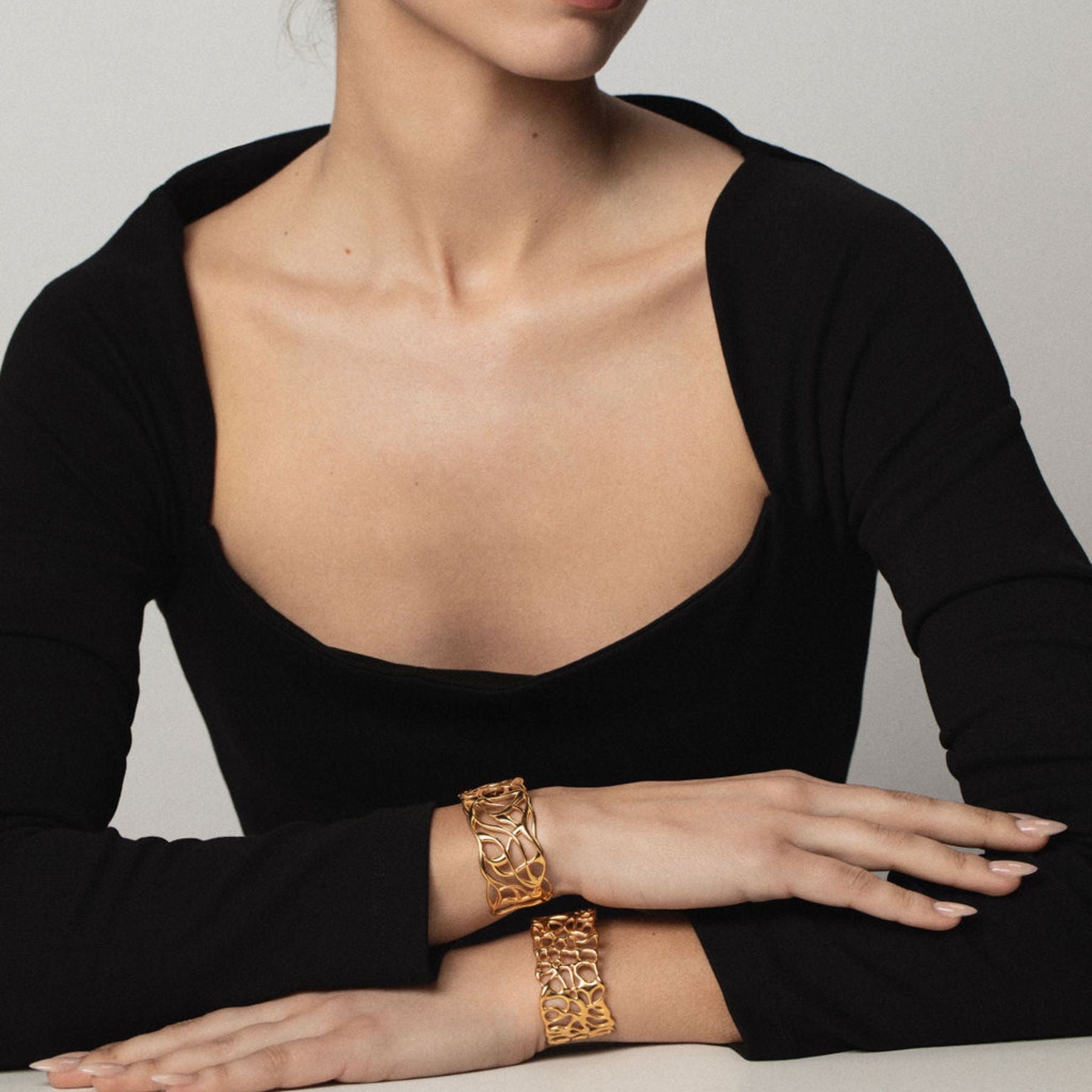 Model wearing a pair of organically fluid cuff bracelets in 18k gold vermeil.