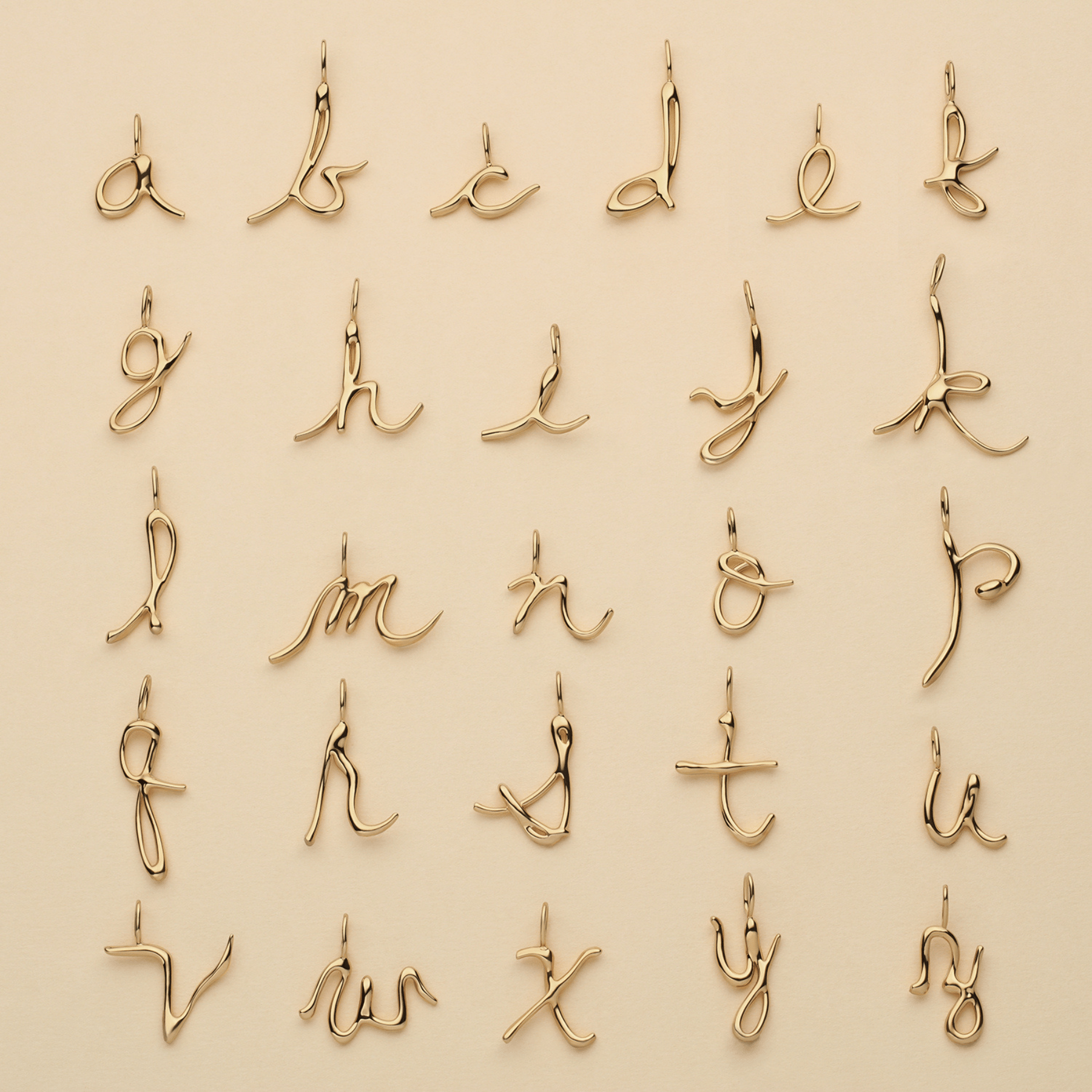Cursive initial pendants in 14k gold.
