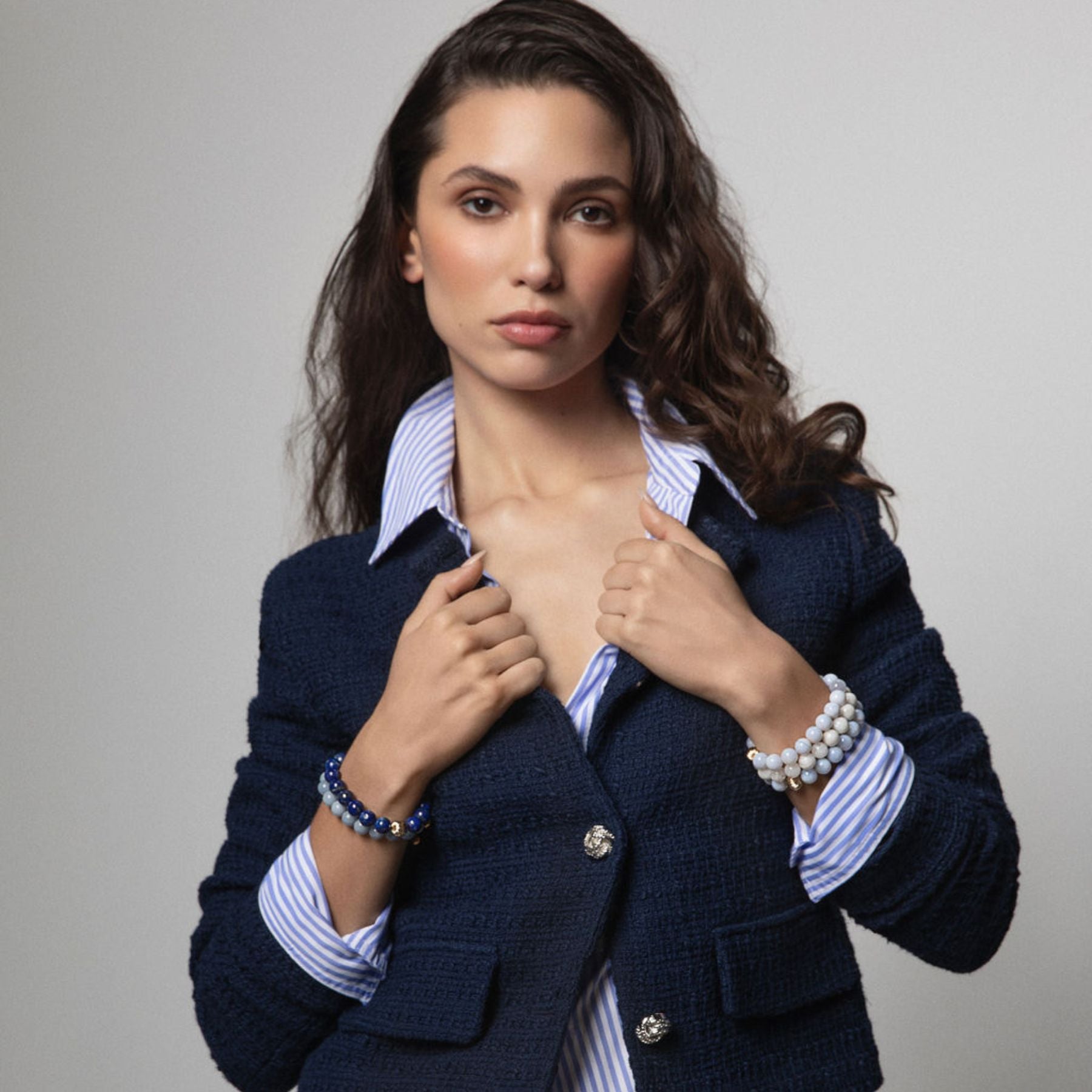 Model wearing stack of blue beaded crystal bracelets.