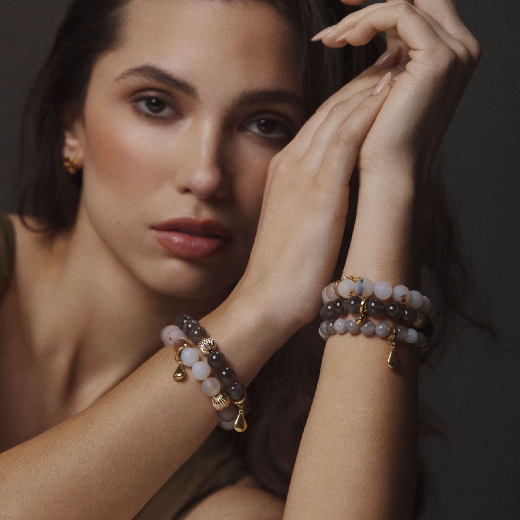 Model wearing stack of black moonstone and agate beaded bracelets.