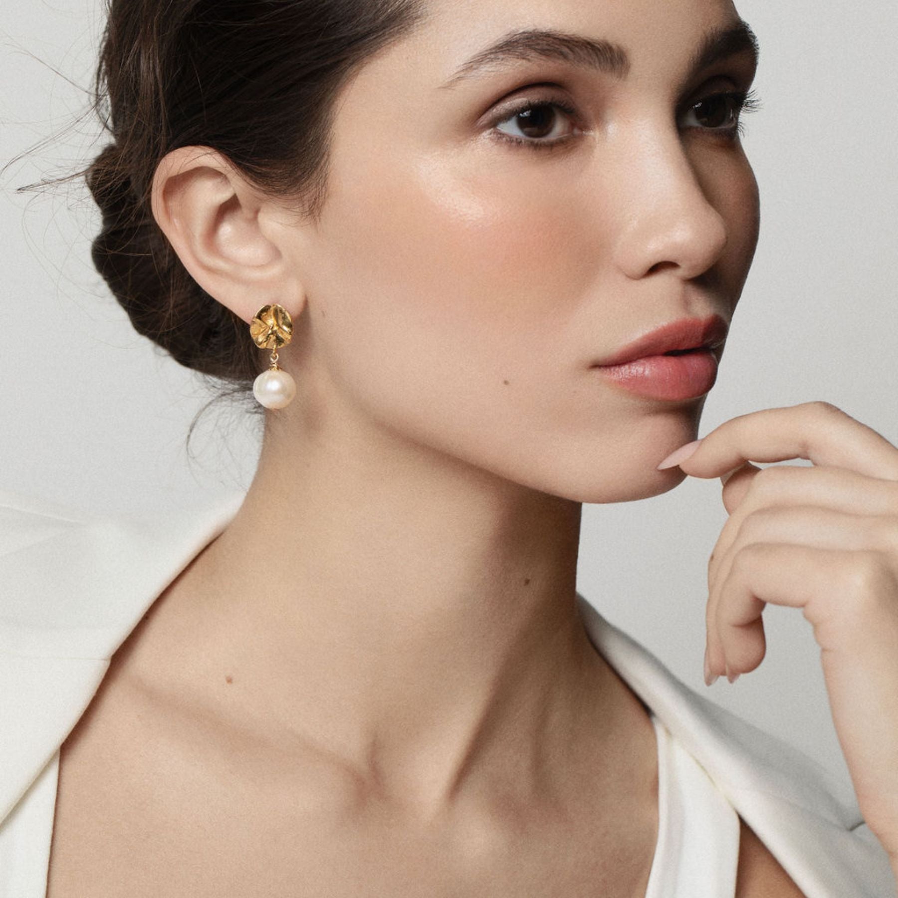 Model wearing Sculptural lily pad-like studs in 18k gold vermeil with a pearl drop.