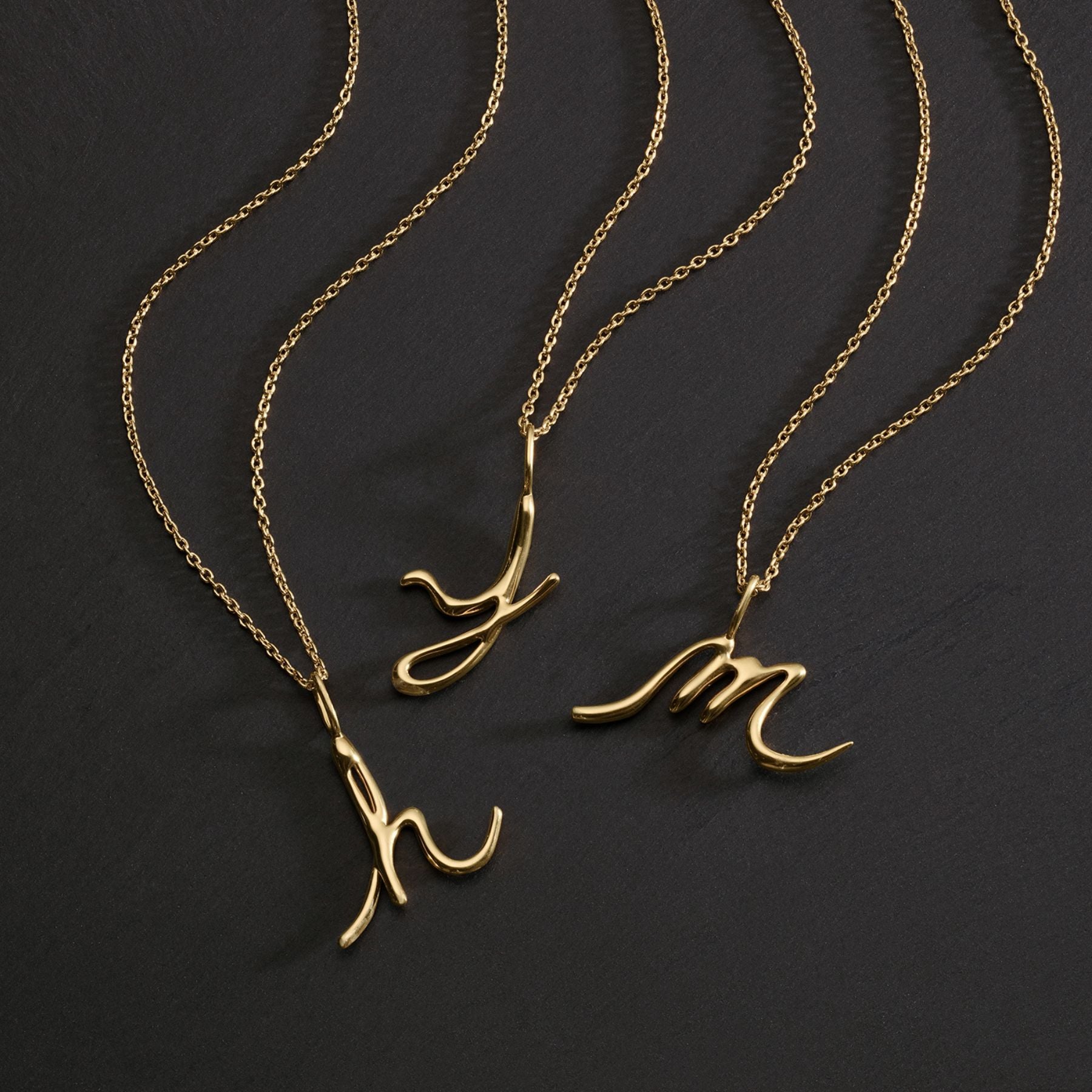 Group of 3 initial letter pendants in 14k yellow gold on gold chains.