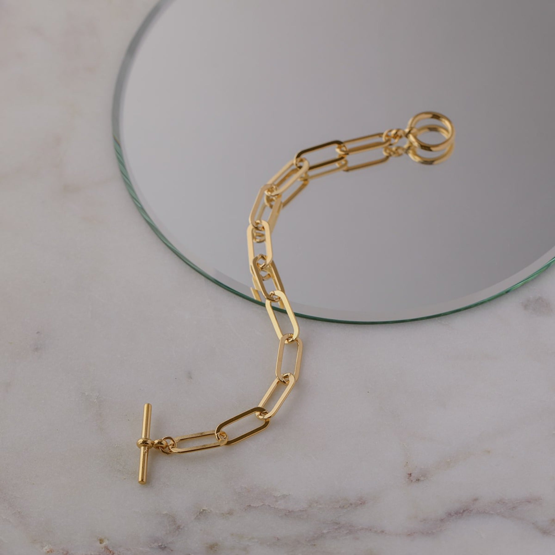 Elongated flattened paperclip chain bracelet with a toggle clasp in 18k gold vermeil.