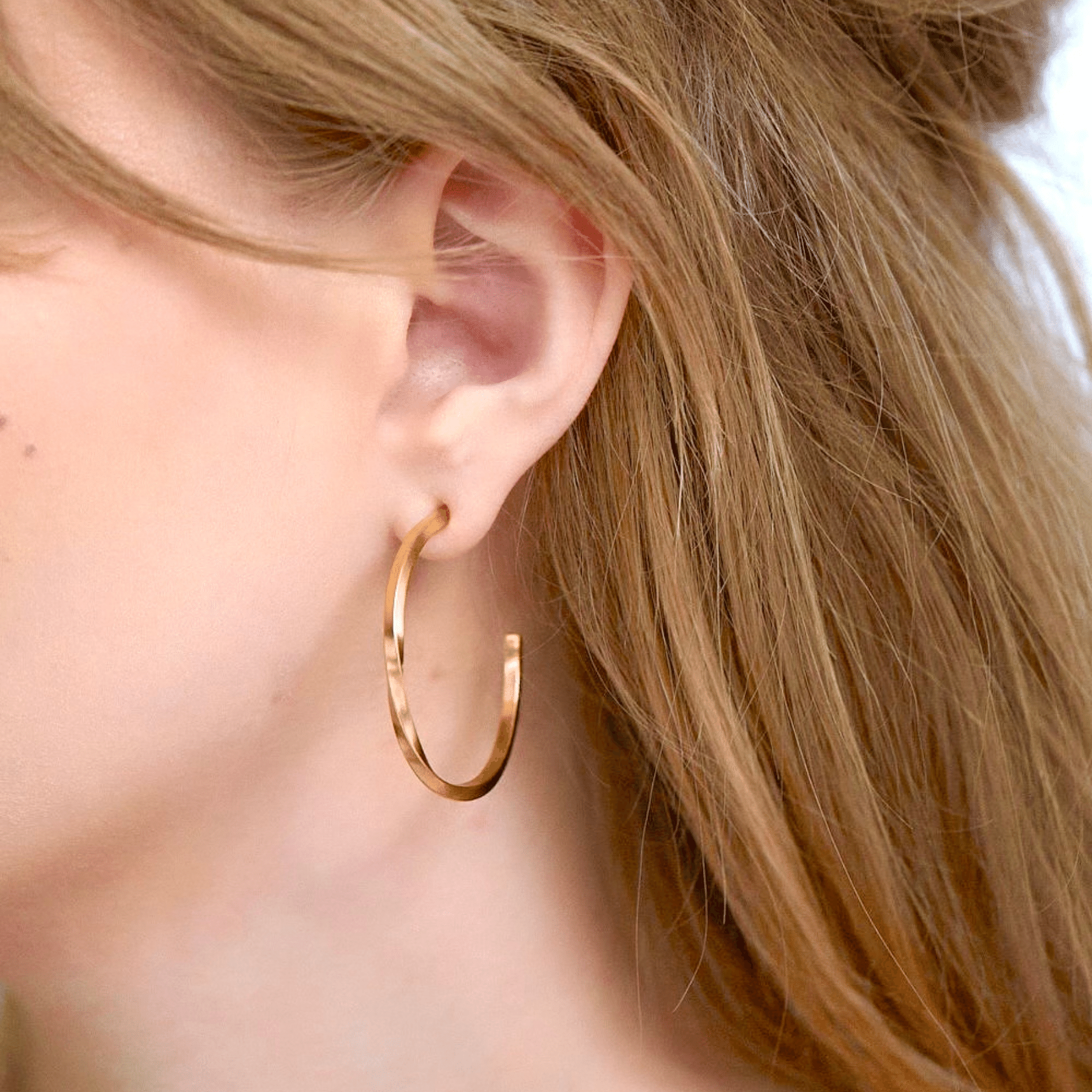 Minimalist medium sized hoop earrings with a single twist in 18k gold vermeil.