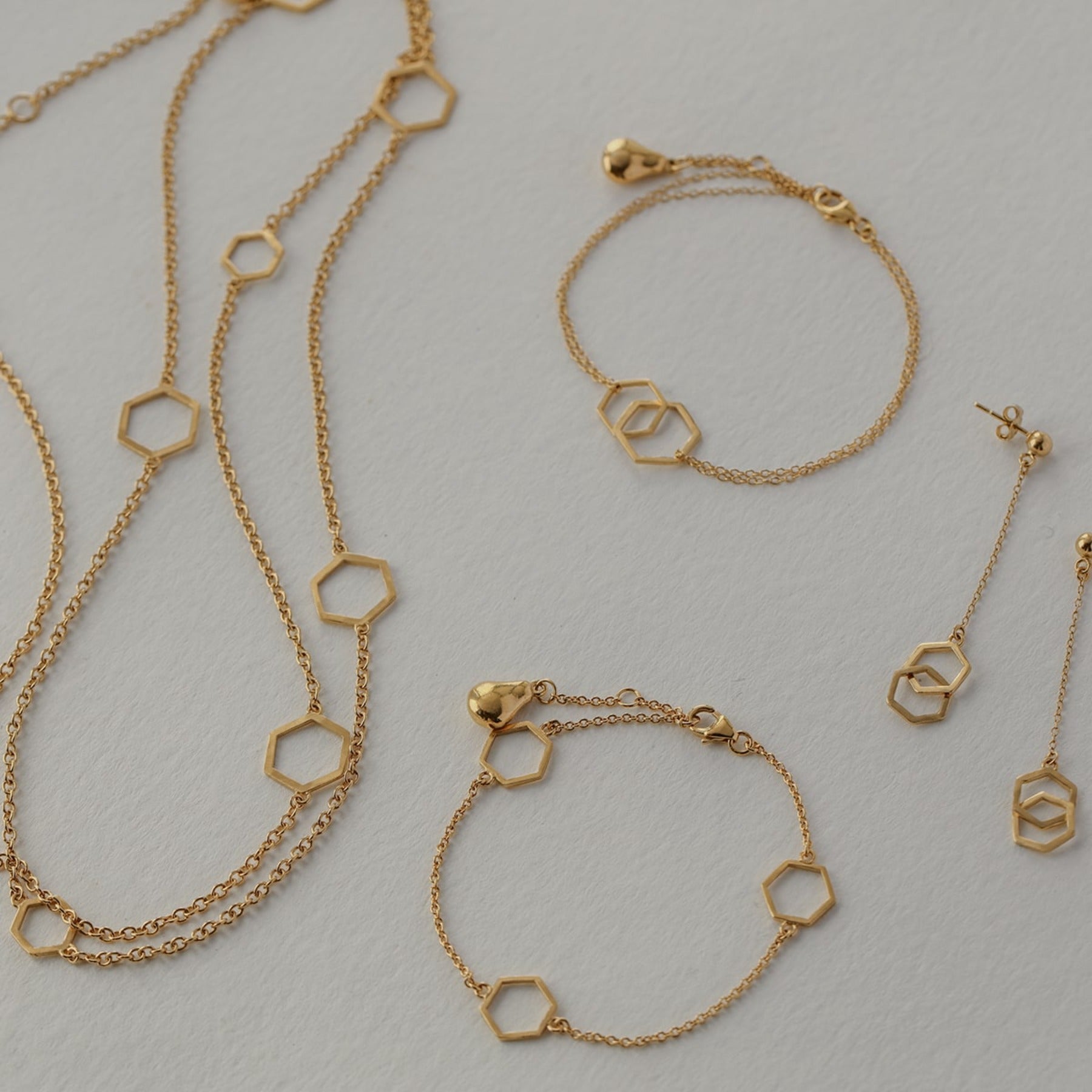 Geometric long necklace with nine large and small hexagons stationed along a cable chain and finished with an Anjou pear charm in 18k gold vermeil.