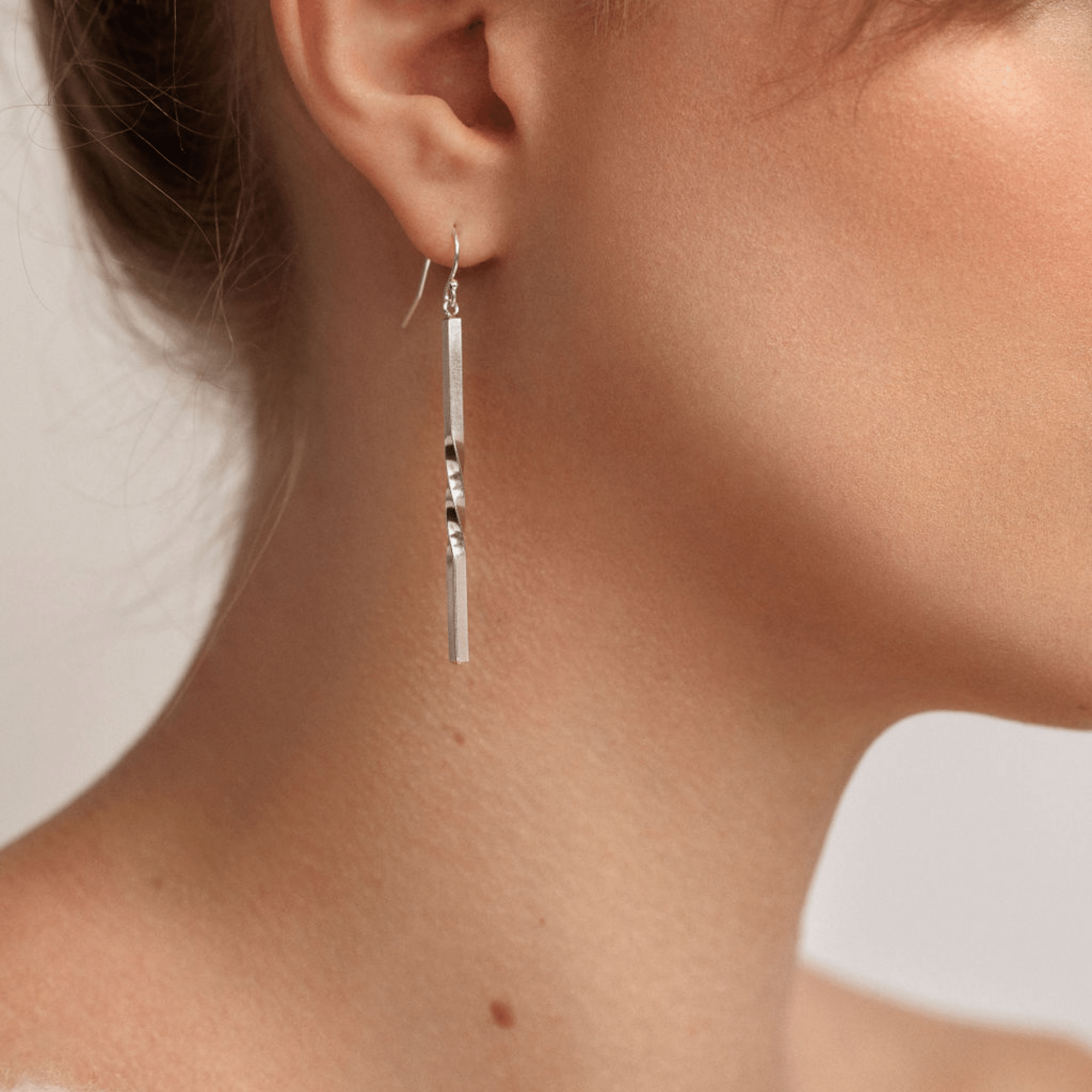 Minimalist vertical bar-shaped earrings with a single twist in the center and a fish hook ear wire in sterling silver..