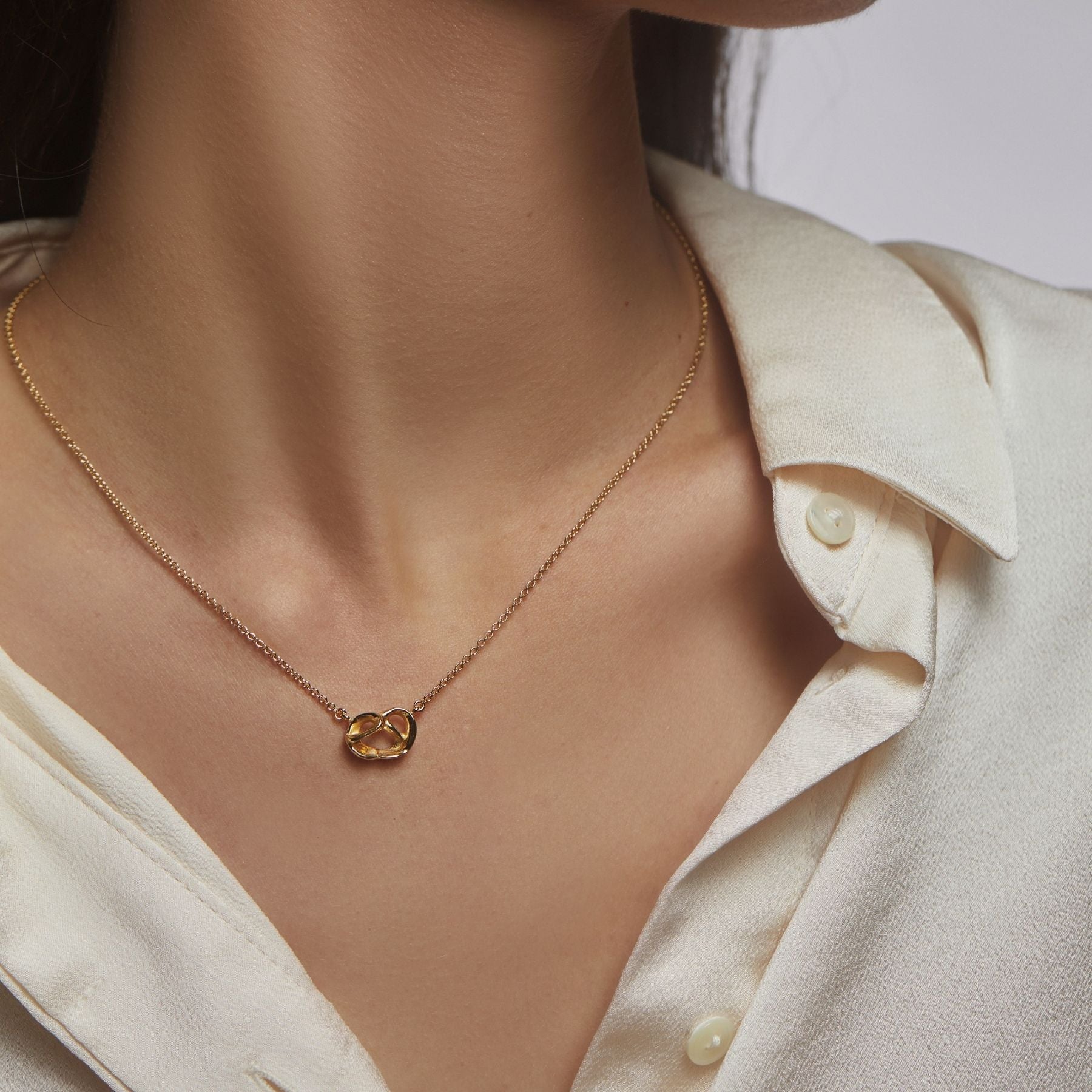 Abstract pretzel pendant necklace on a delicate cable chain finished with an Anjou pear charm in 18k gold vermeil.